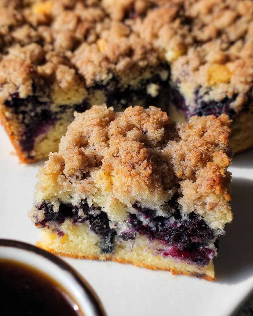 Blueberry crumb cake with a golden brown streusel topping and a moist, fruity interior filled with fresh blueberries. Perfect for breakfast or a sweet snack.