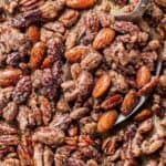 Sugar-coated spiced pecans with a crunchy texture, perfect for snacking or garnishing desserts, showcased in a close-up image with a metal scoop.