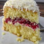 Fluffy layered vanilla sponge cake with cherry filling and creamy frosting, topped with white chocolate shavings. Perfect for special occasions and celebrations.