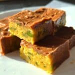 Golden lentil and vegetable savory squares with a melted cheese topping, served on a white plate, perfect for healthy snacking or meal prep.
