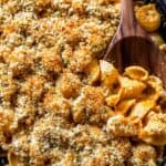 Creamy baked mac and cheese with golden breadcrumb topping in a cast iron skillet, served with a wooden spoon for a comforting, cheesy family favorite.
