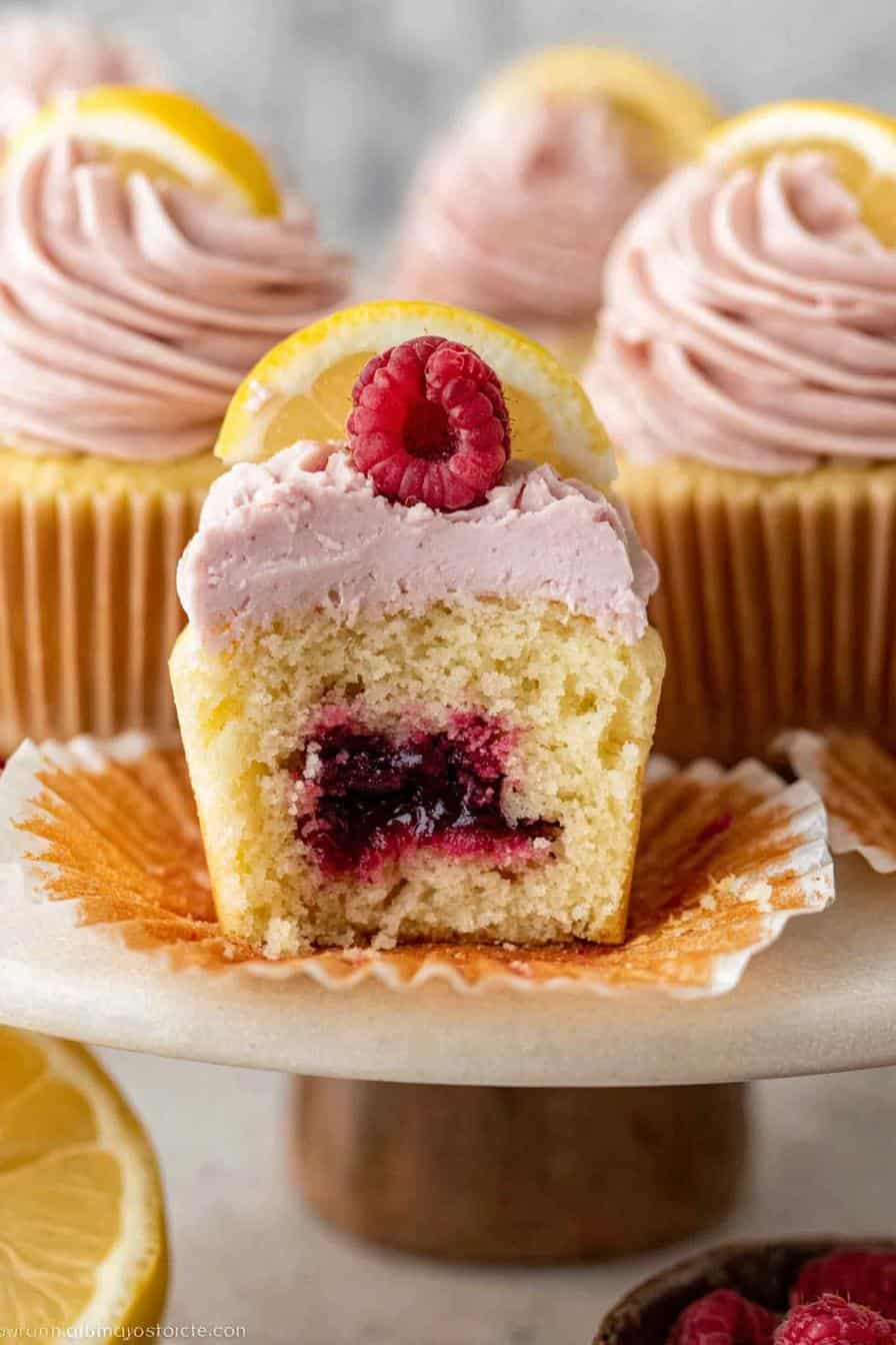 Lemon raspberry cupcakes with pink frosting, garnished with lemon slices and fresh raspberries, perfect for dessert or special occasions.