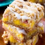 Sweet peach cobbler bars with crumbly topping and creamy peach filling, perfect for summer desserts and bakery treats. Fresh baked peach dessert bars topped with icing drizzle.