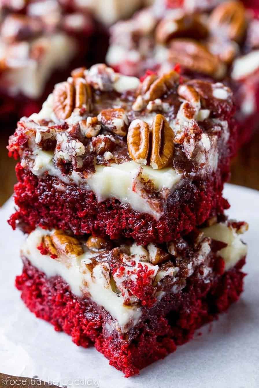 Gooey red velvet cake brownies with cream cheese frosting and pecan topping, close-up shot, rich chocolate dessert, decadent baked good, homemade bakery style treats.